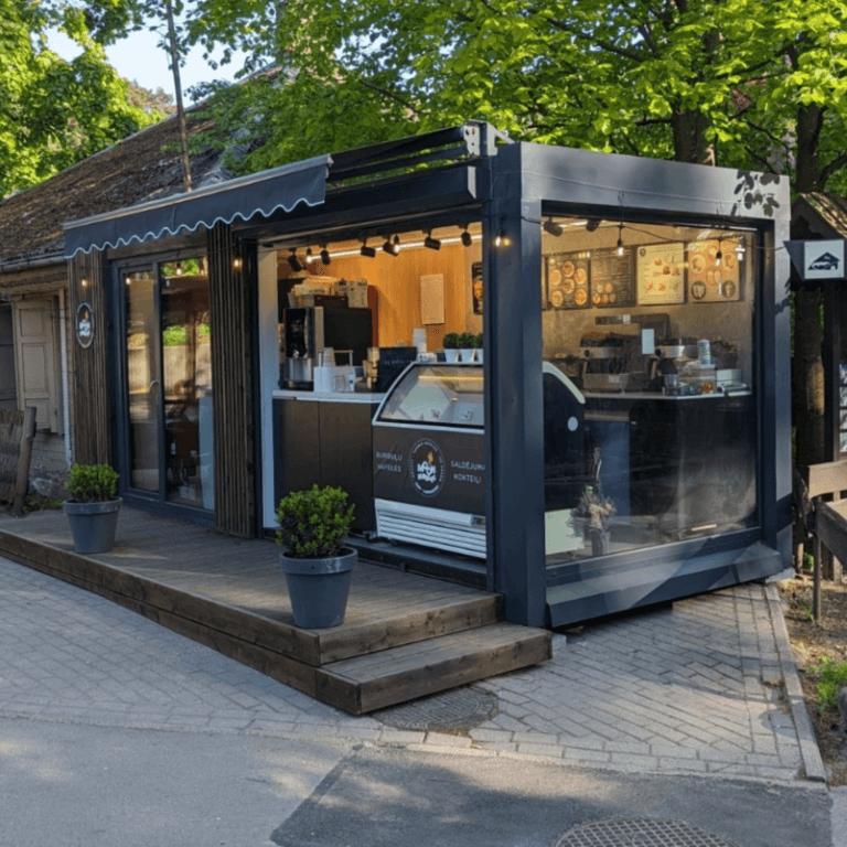 Retail container building used as a cafe kiosk with glass walls, awning and a wooden deck
