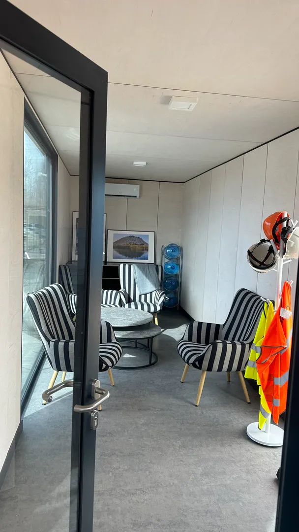 Shipping container module interior with a safety gear rack, armchairs and air conditioning