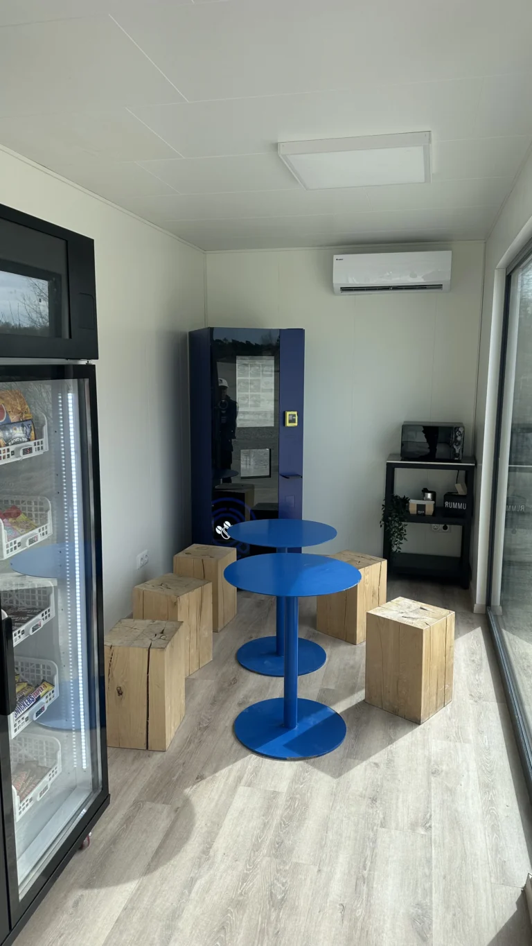 Self service shop container interior with vending machines, fridges and a seating table