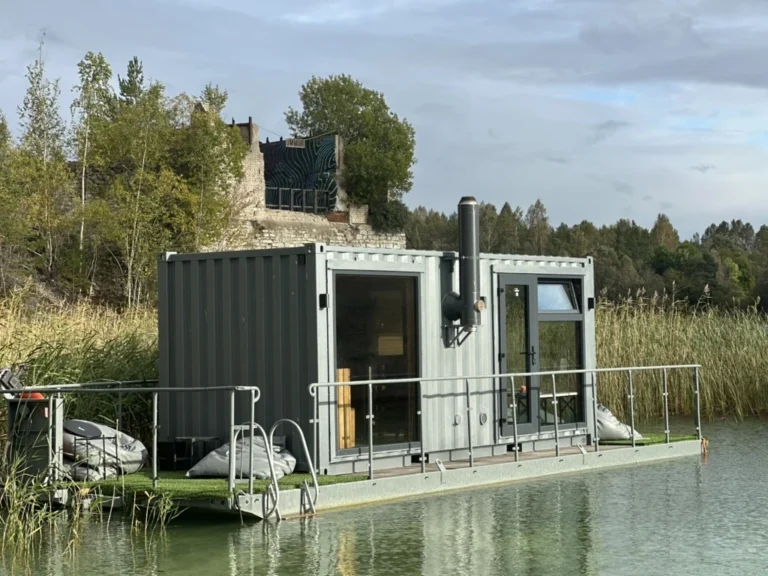 Side view of the Usinsh IV sauna by the water with the stove chimney and railings